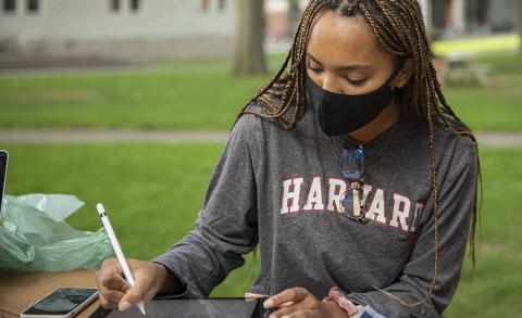 Student wearing a mask sitting outside doing homework