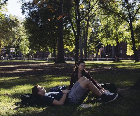 Two students sit In Harvard Yard.