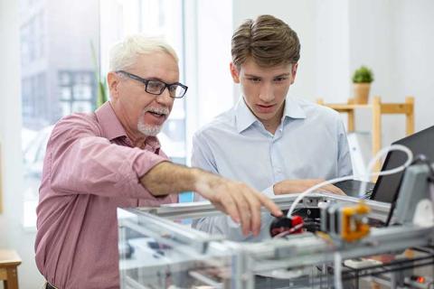 A male professor and student at a 3D printing machine