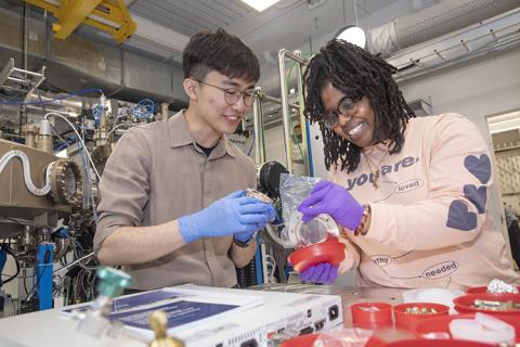 Two students working in a lab. 	