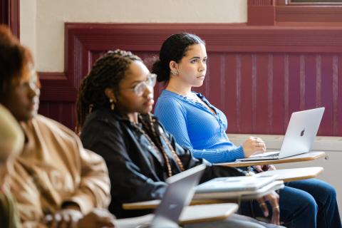 Students look up from the laptops on their desks to listen to their professor during lecture in Sever Hall.