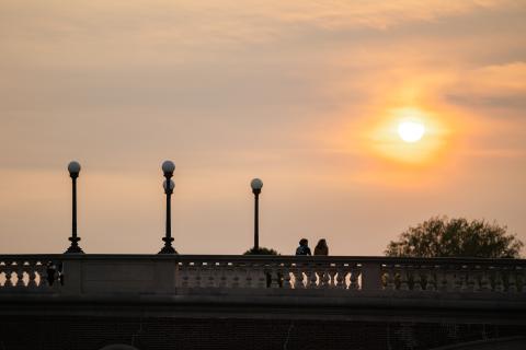 Two students enjoy the sunset sitting on the ledge of Weeks Bridge.