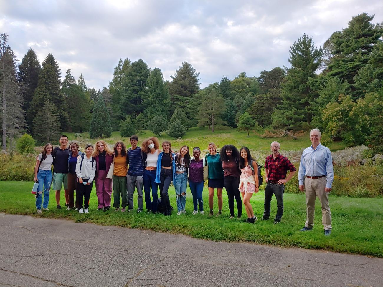 Group picture of students and professors standing beside a road and smiling at the camera.
