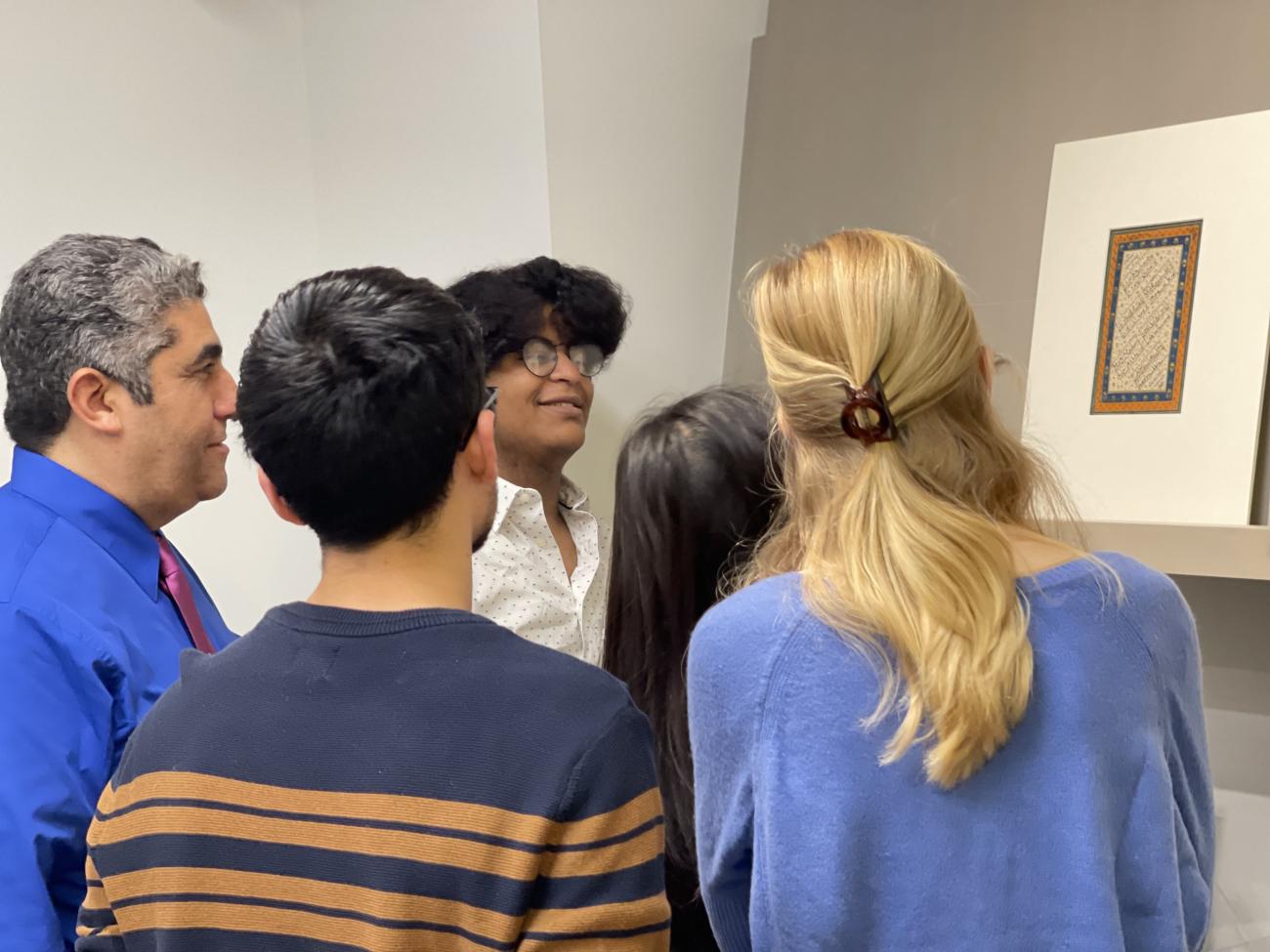 Four students and professor looking at a manuscript