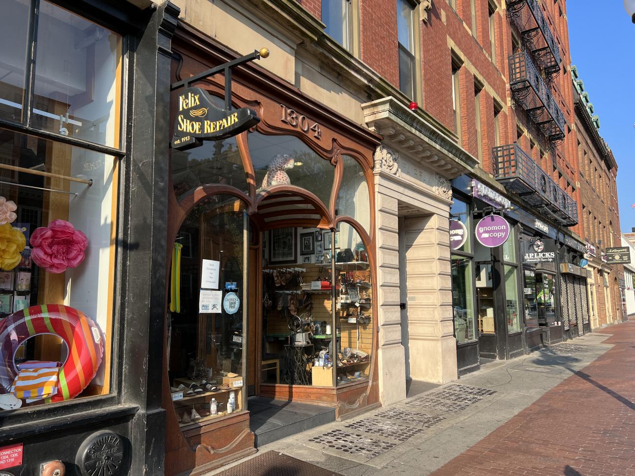 Photo of Felix Shoe Repair storefront which has large glass windows and intricate wooden window casings