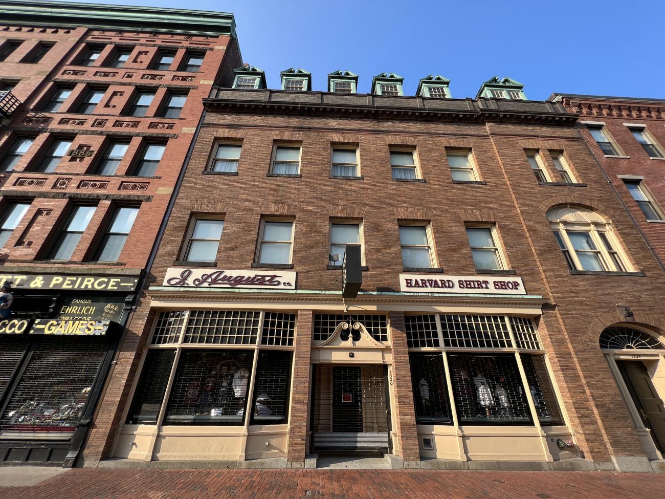 Photo of J. August. Company storefront located in an organ brick building and decorated with large bay windows displaying merchandise