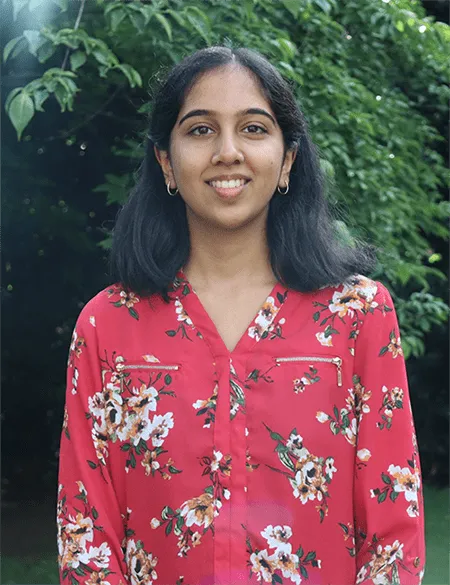 Headshot of Nurayda Albeez ’29, wearing a red floral shirt against a greenery background.