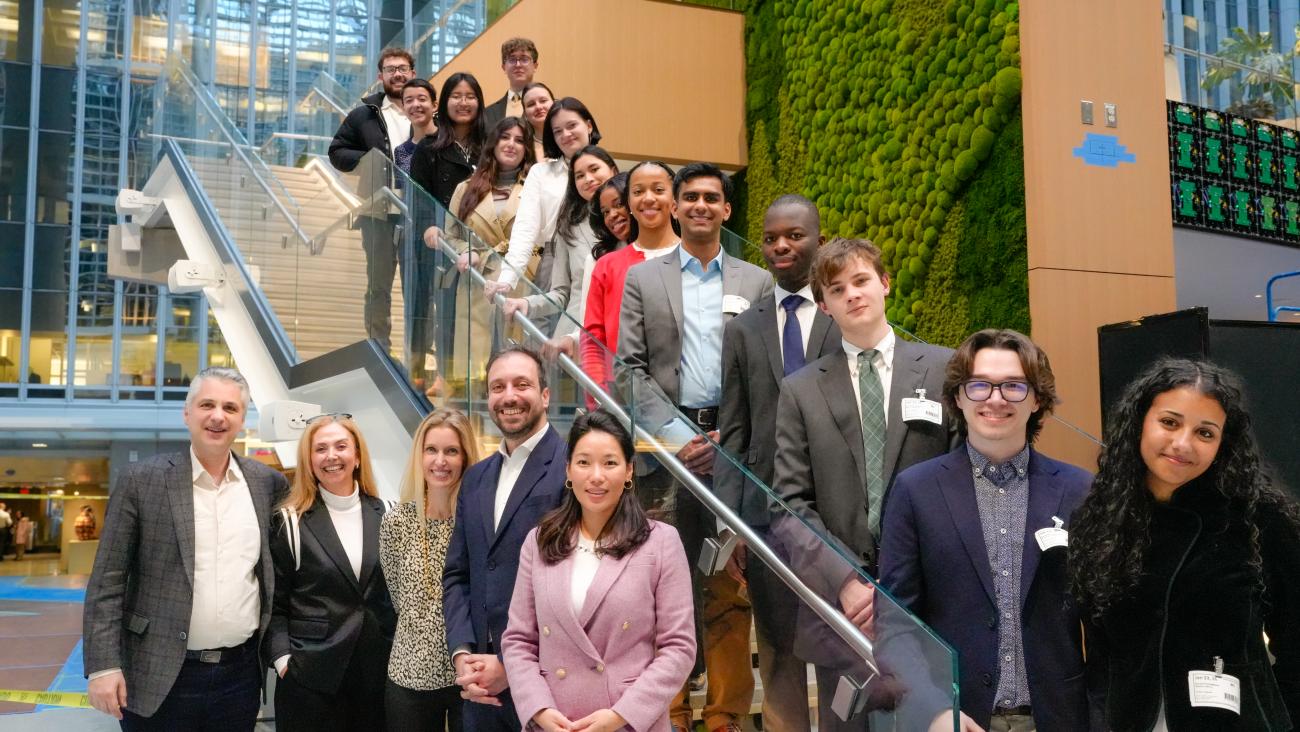 The group of students standing on a railing with the supporting facility standing next to them.