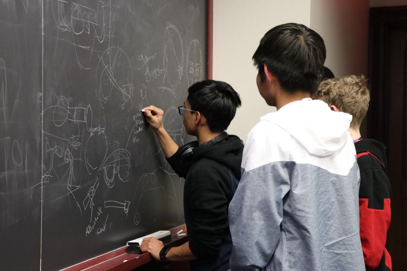 students working on a problem on a chalkboard