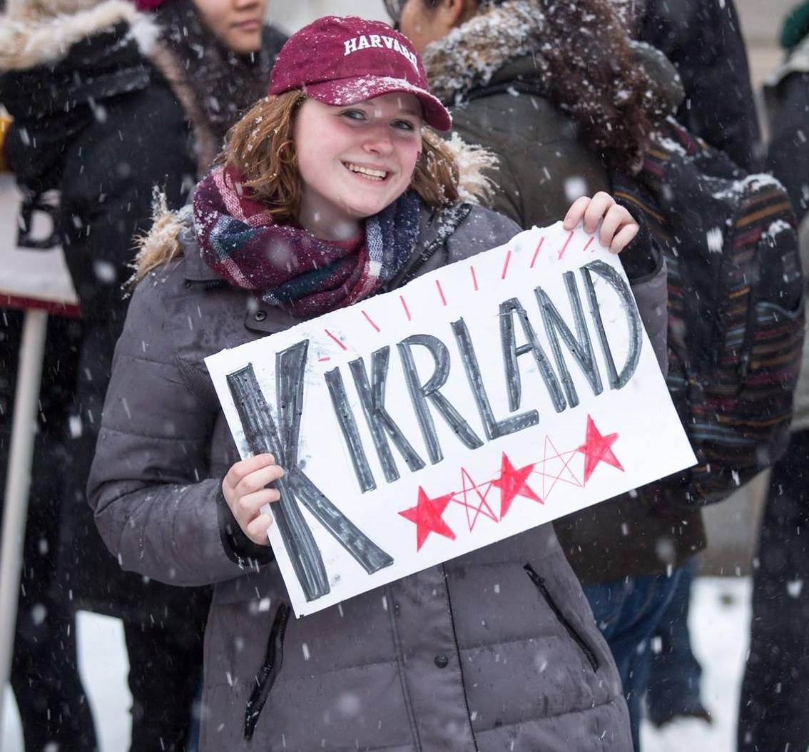 student holding sign that says "Kirkland" for Kirkland House on Housing Day