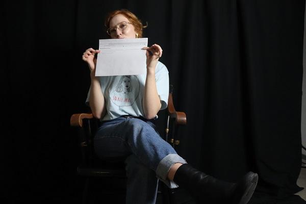 student in a chair and holding a piece of paper