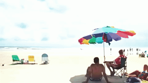 Screenshot of a couple sitting on a beach under an umbrella