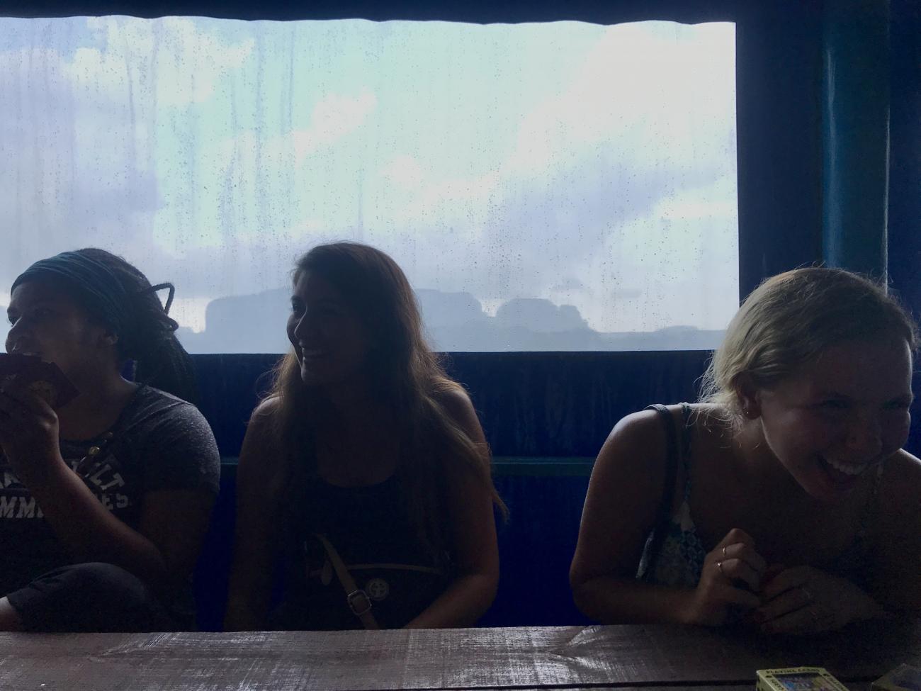 students laughing as they wait for the rain to stop.
