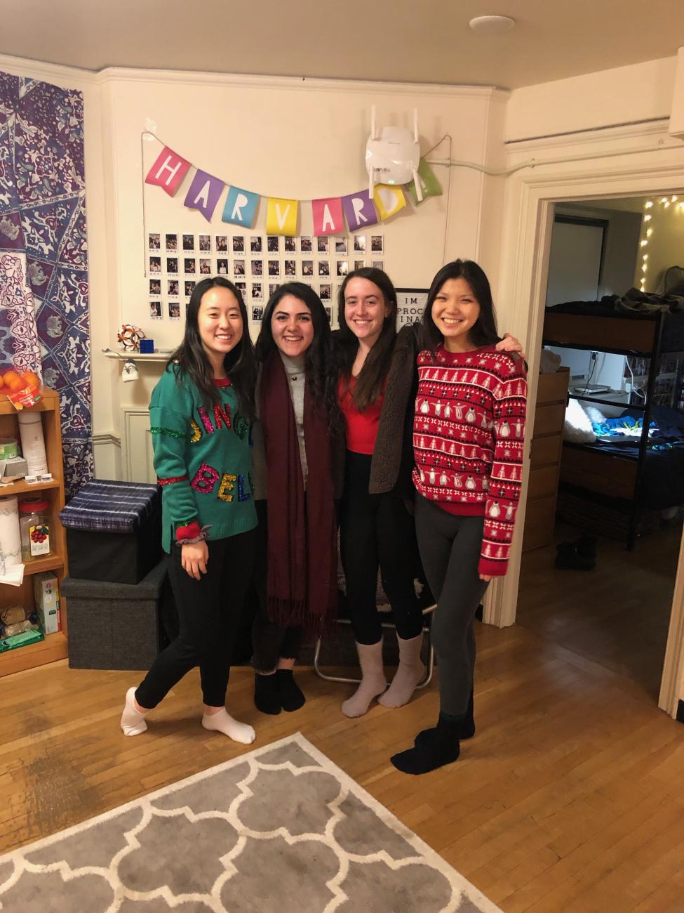 four students pose in dorm room