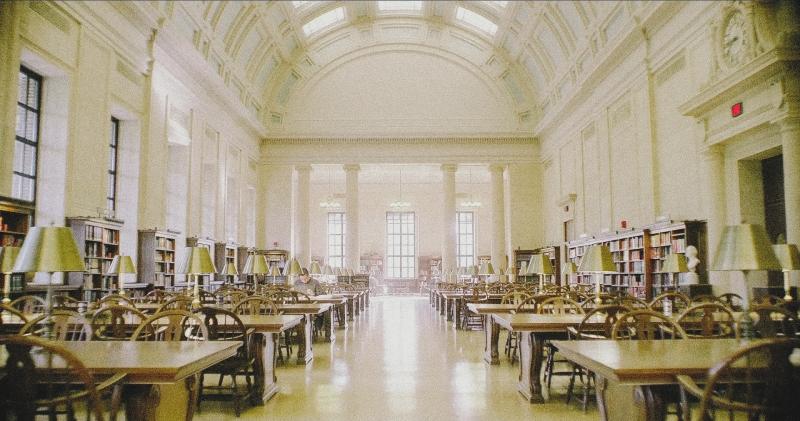 Interior shot of a Harvard Library, a large white room with a single studying student.  
