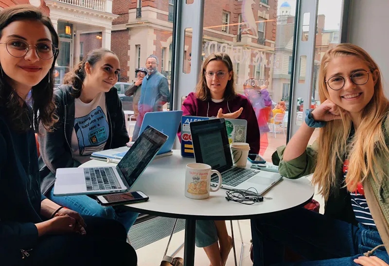 4 female students at a table on their laptops