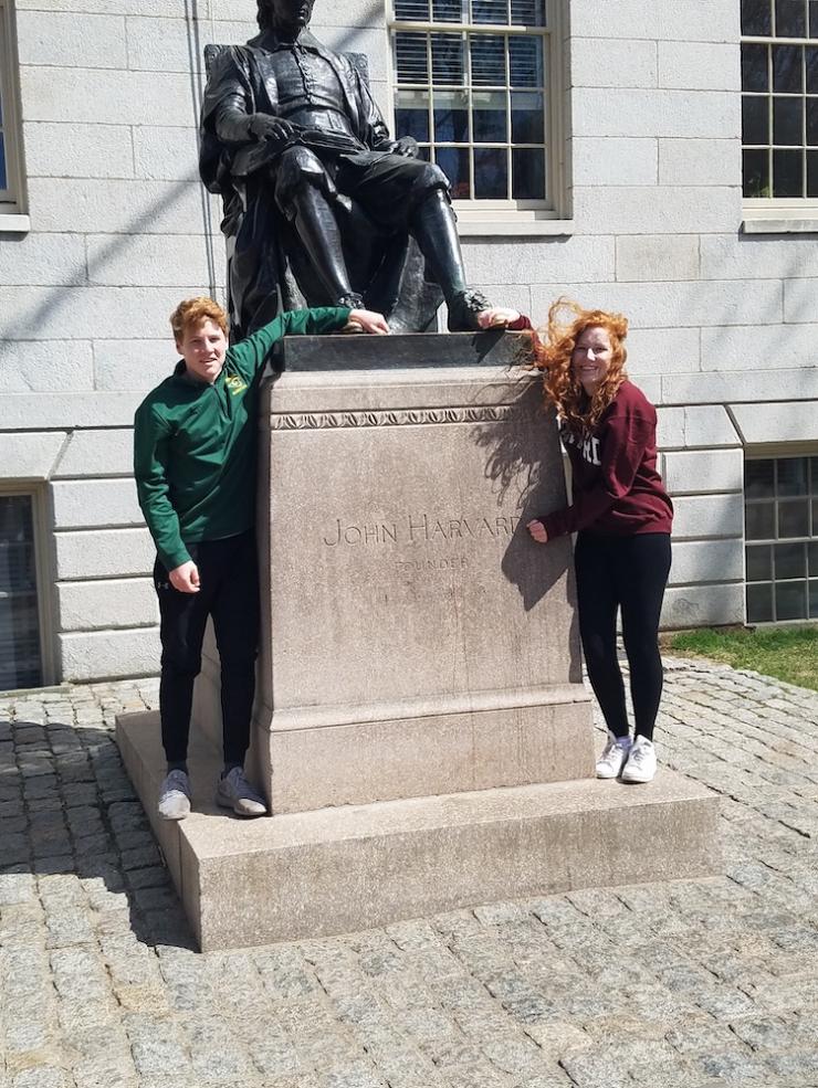 Allison and her brother posing with the John Harvard Statue