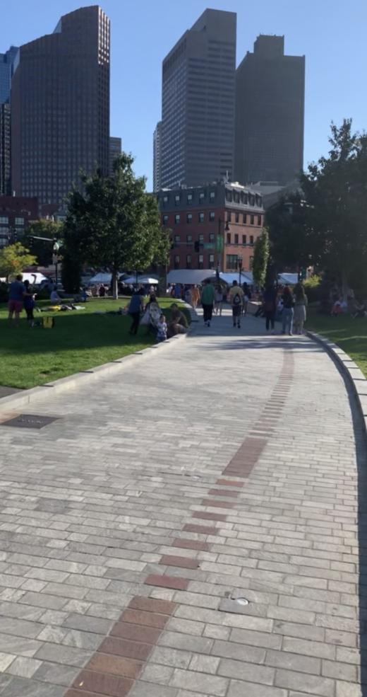 A pathway leading to white tents and tall buildings