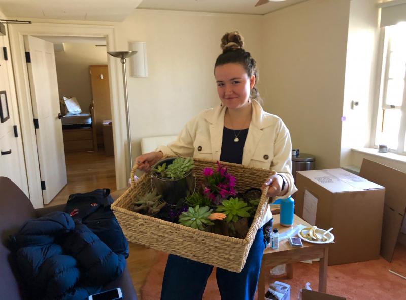 Female student holding plants in dorm room
