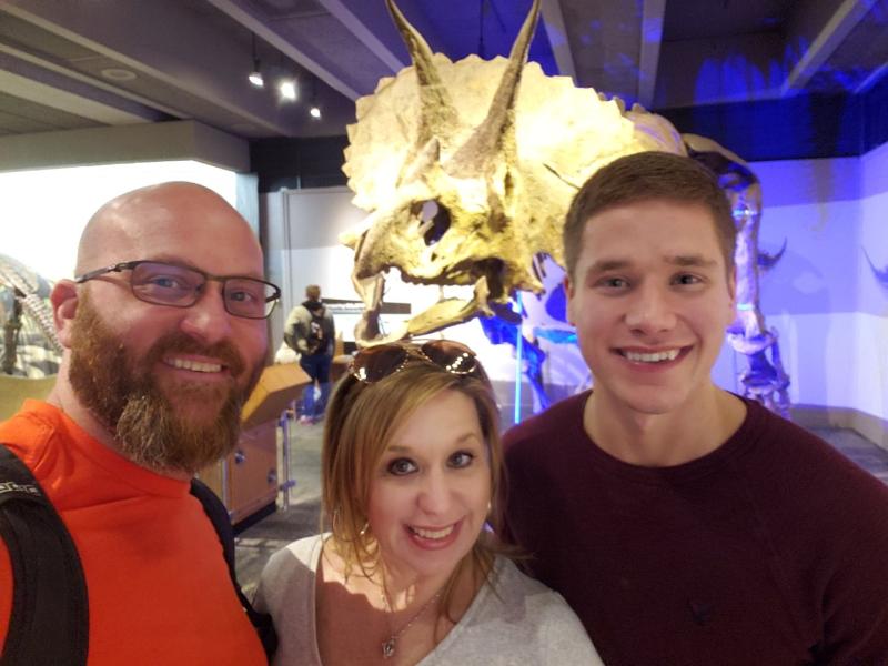 Family posing in front of dinosaur fossil