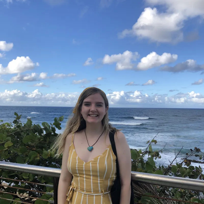 The author of this post standing in front of a guardrail, ocean and trees in the background.