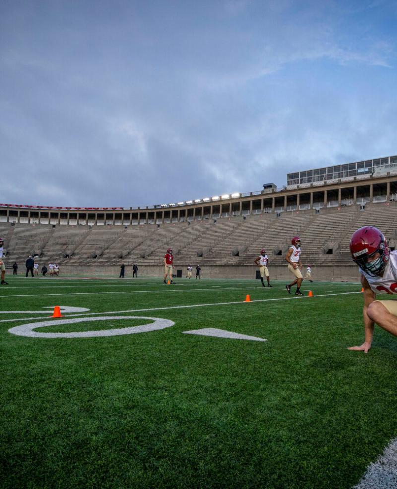 Defensive back Garrett Sharp '24 does an end-of-practice drill with his teammates at sunup in Harvard Stadium.