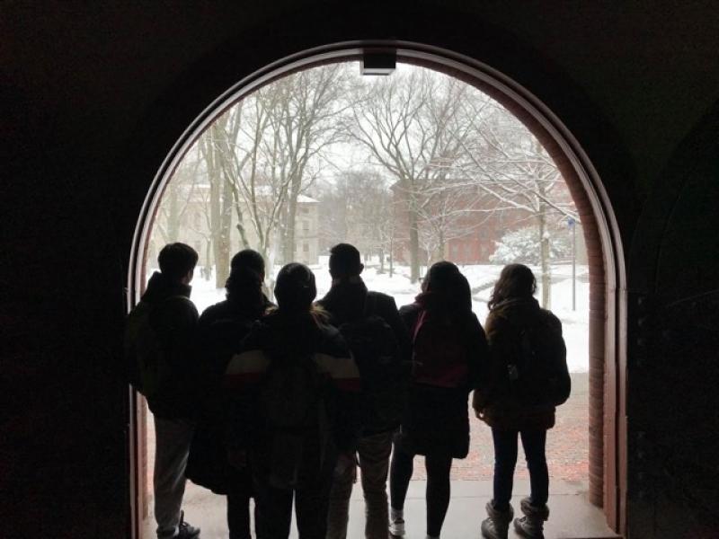 A group of students standing at a doorway looking at snow