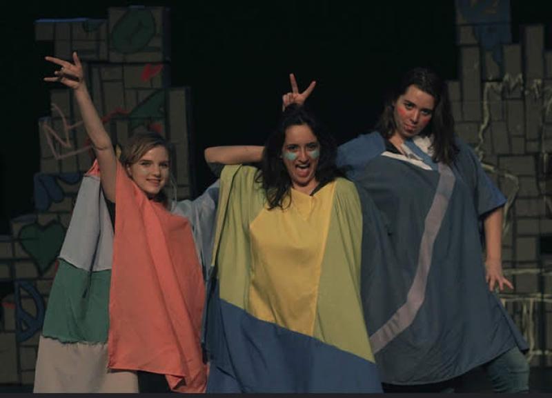 Three actors in colorful costumes smiling and posing