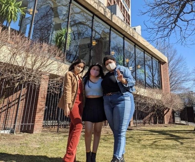 Three girls standing outside a building.