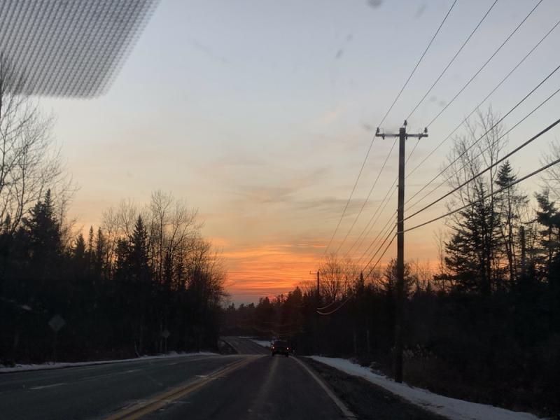 view out the car window of the sunset at the end of a long country road