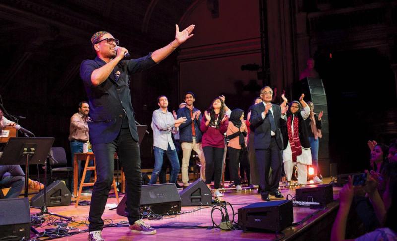 Ali Sethi brings the Sanders Theatre crowd to its feet during a concert last spring. His Harvard mentor, Ali Asani (right, in suit and tie), joined him on stage.