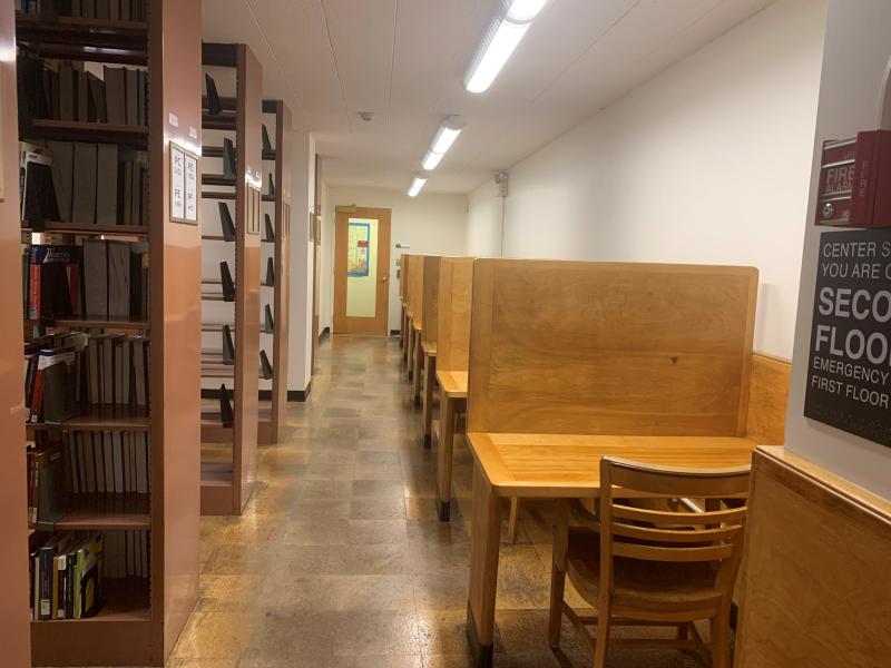 Wooden booths along a wall next to bookshelves.