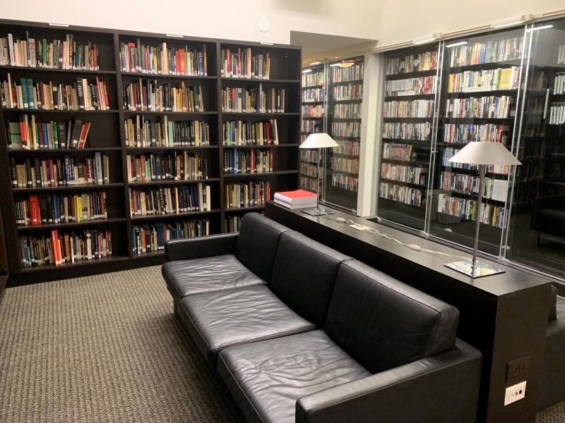 Two black couches surrounded by bookshelves.