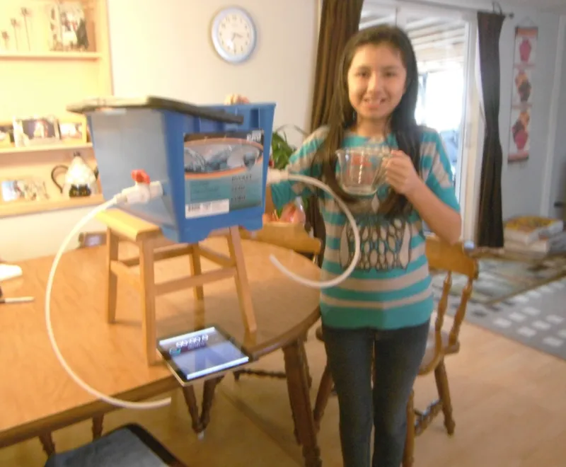 A girl standing next to a mechanical model of a human heart.