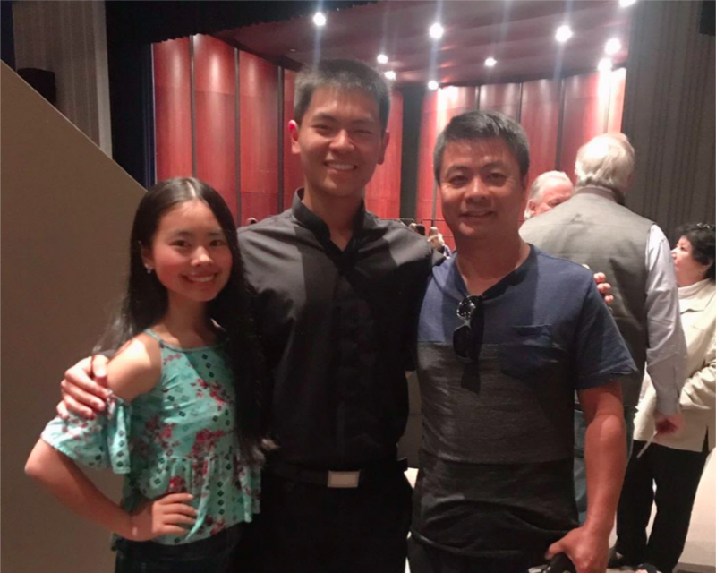 A picture of Raymond Zheng, his father, and his sister in a theater.