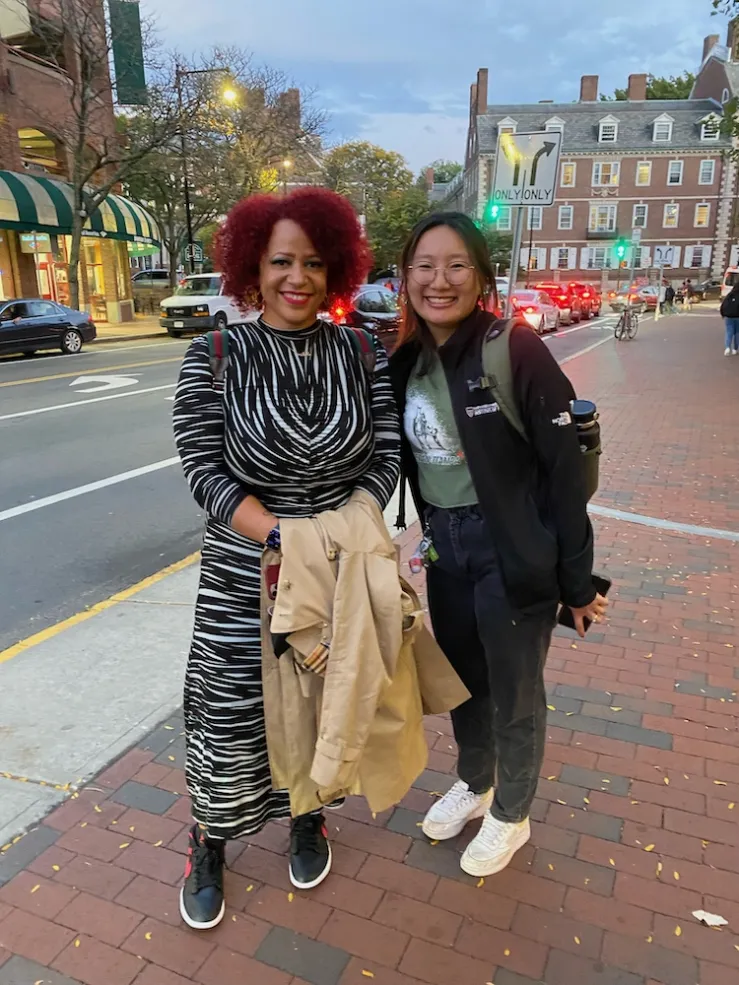 two individuals standing next to each other on sidewalk smiling