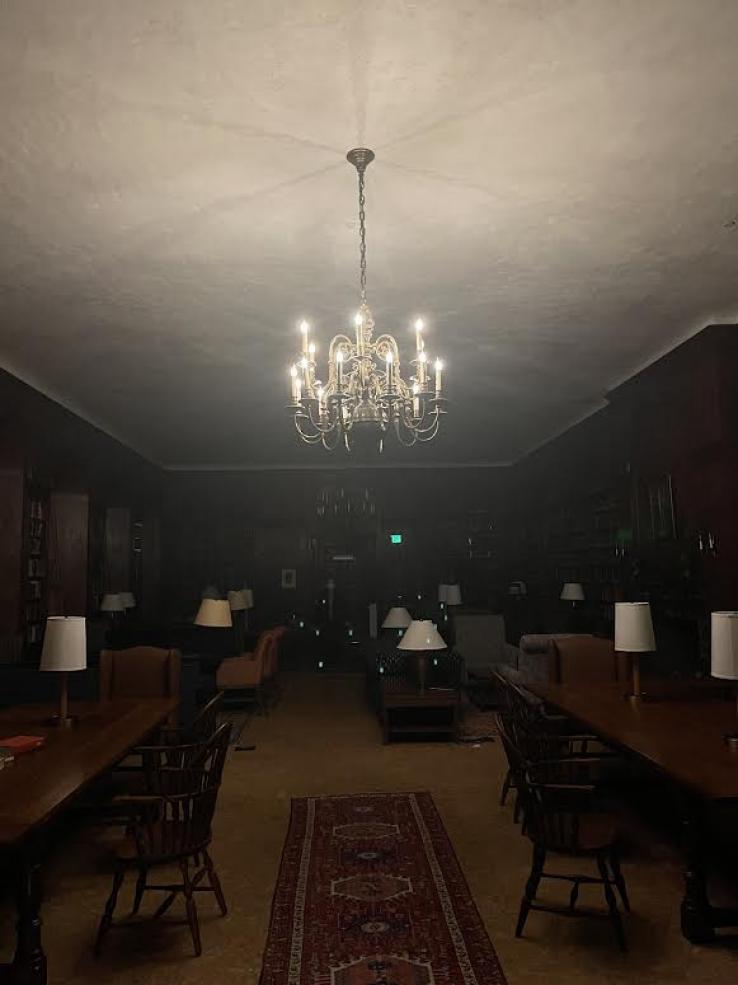  A photo of Lowell Library. All the lights are off except for a chandelier in the center of the room.