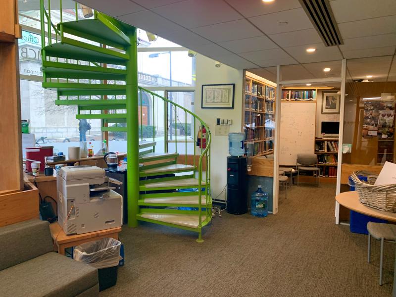 An office space with a green spiral staircase on the left.