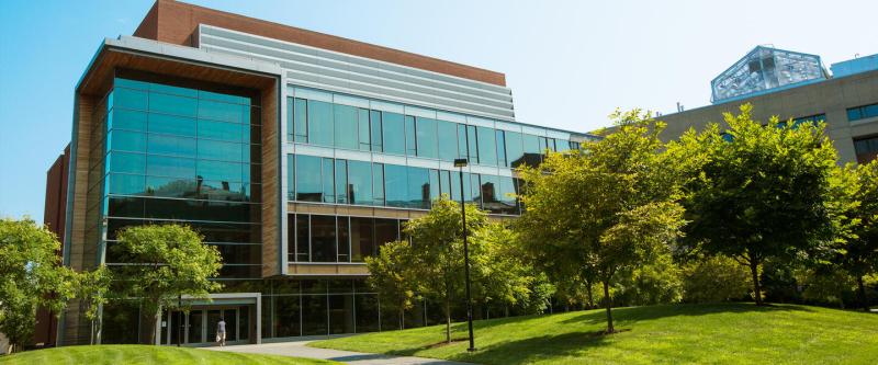 A building with glass panes and a grassy field in front.