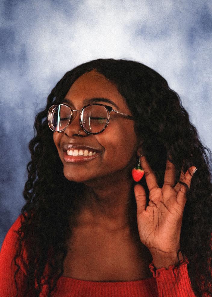 Portrait of female student smiling holding a strawberry earring