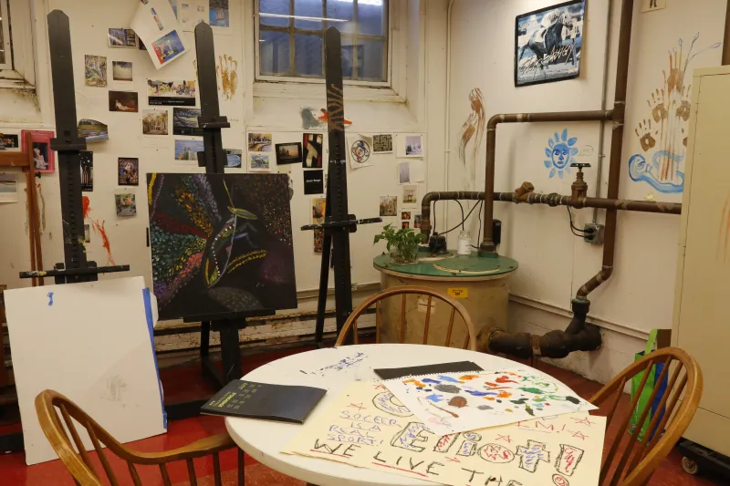 A table with drawings on top and 3 easels in the background