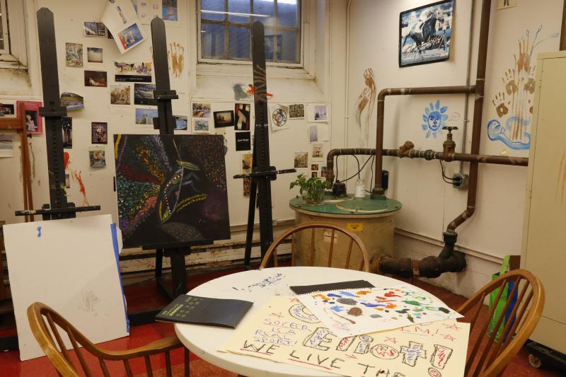 A table with drawings on top and 3 easels in the background