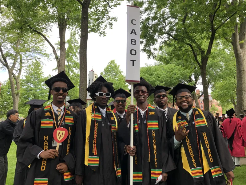 group of students wearing cap and gowns and holding a cabot sign on Commencement day