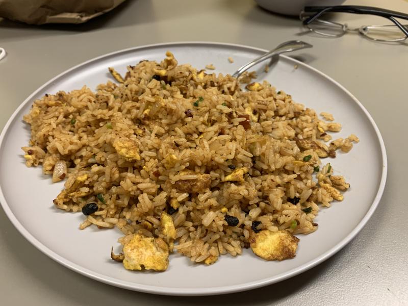 Picture of a plate of fried rice on a plastic plate with a spoon.