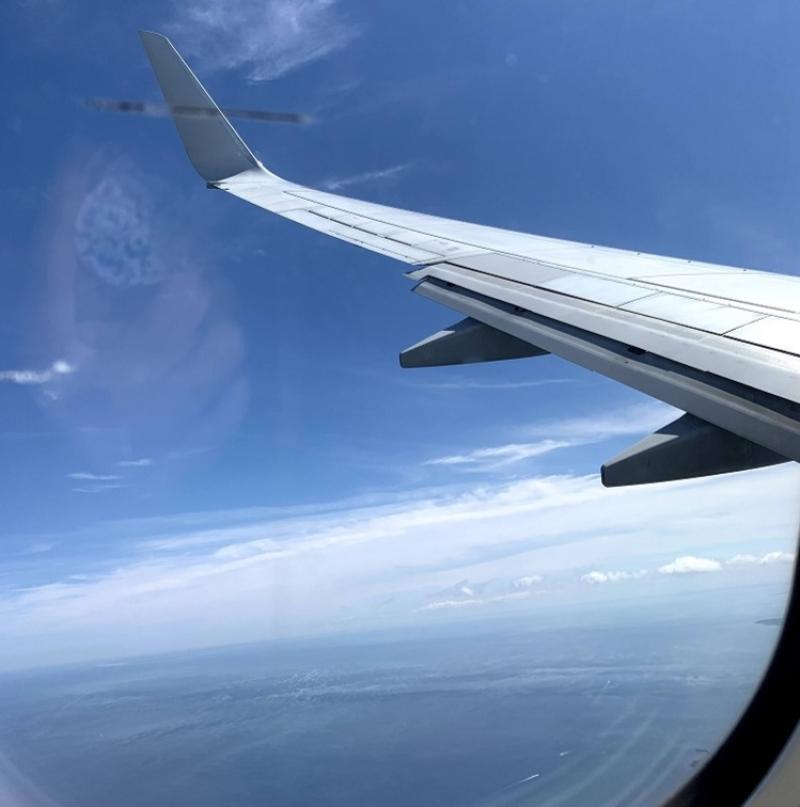 The wing of a plane in a blue sky.