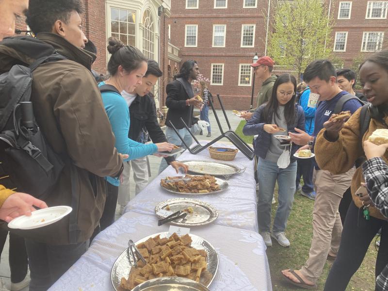 A picture of students gathered around a table, taking desserts and talking. 