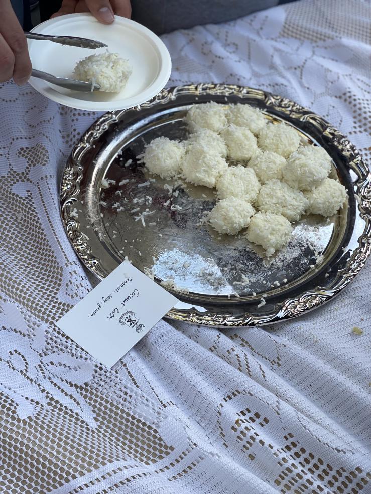 A picture of a student’s hand taking a dessert off a silver platter with tongs.