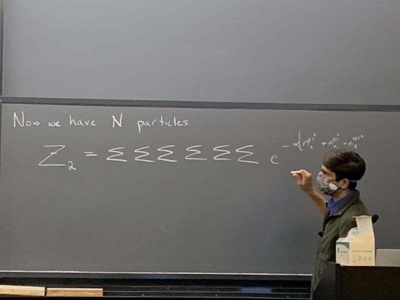 Professor drawing sigma symbols with chalk on a blackboard.