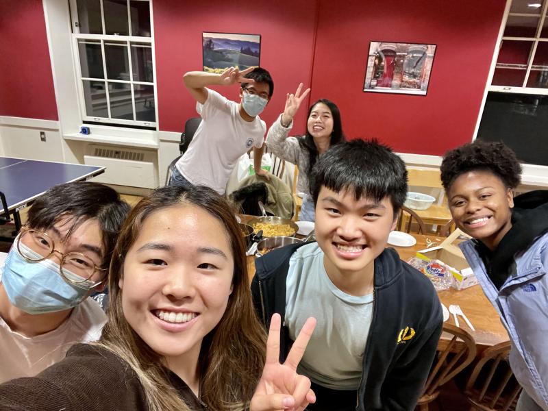 A selfie picture with Raymond and his friends standing around a table with food.