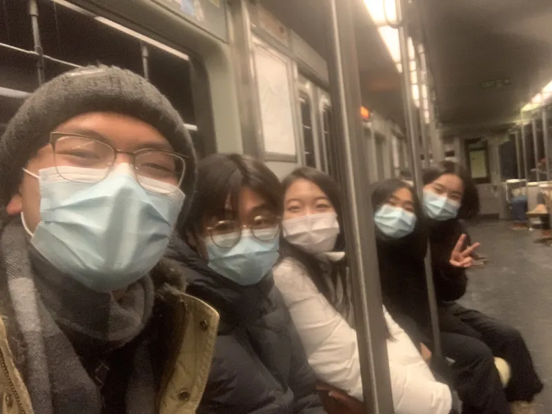 Students sitting on a Boston subway smiling at camera.
